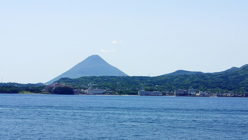 錦江湾越しに見る指宿温泉の街並みと開聞岳の写真。